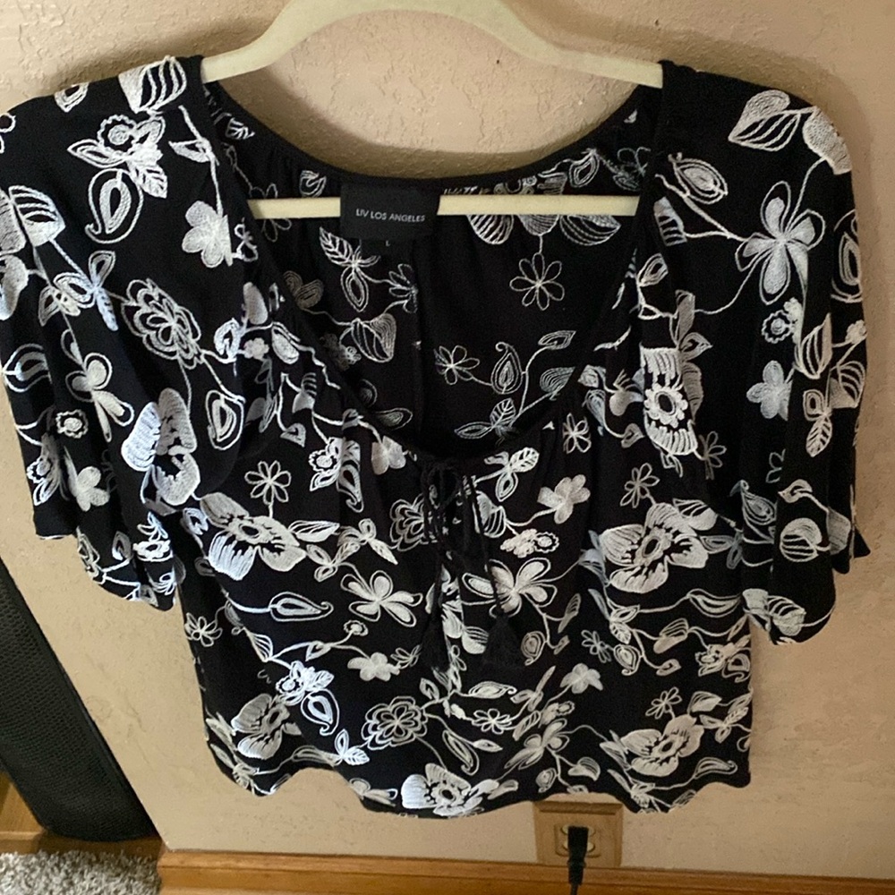 Short sleeved black shirt with white flowers and tie at neck in the front